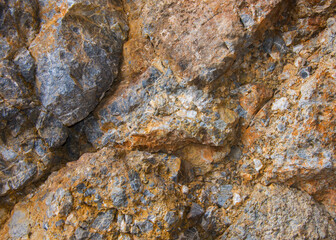 The rough surface of the cliff with inclusion of stones of different rocks.