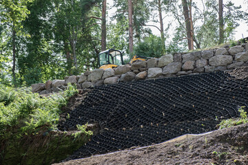 Security concept. Strengthening the mountain slope with construction equipment, artificial mesh, geogrids that prevent rockfalls and landslides of mobile and loose soils.