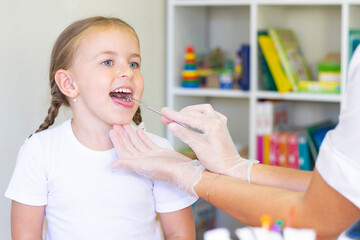Speech therapy massage of the girl's tongue. a speech therapist makes a tongue massage to a child with a staging probe.