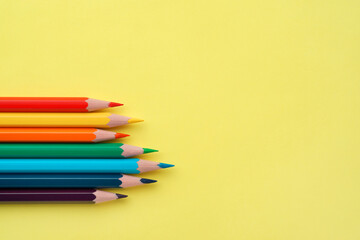 Colorful pencils on yellow paper