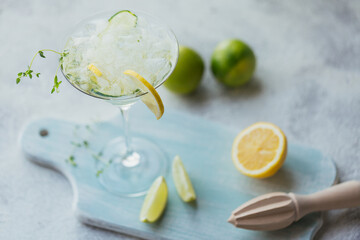 Summer alcoholic drink. Homemade refreshing cocktail with gin, vodka or tequila, cucumber, lime, ice cubes and thyme on a wooden background