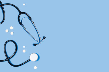 Blue background with stethoscope and tablets. Top view of medical equipment. Flat lay, copy space.