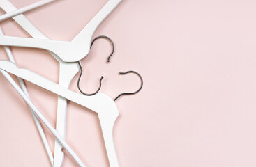 White wooden hangers on a pastel pink background. Geometric composition with space for text, top view. The concept of a summer sale, conscious consumption in the fashion industry