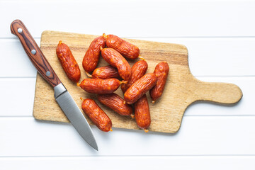 Mini salami sausages on wooden cutting board.