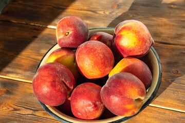 ripe peaches in an iron bowl on a wooden background