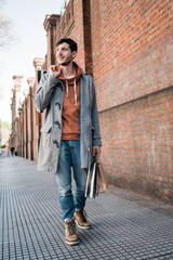 Fototapeta na wymiar Young man holding shopping bags while walking on the street.