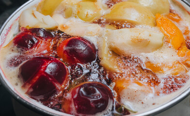 Fruit compote: apricots, plums, apples, cherries are cooked in a metal pan in boiled water with bubbles. Making juice.