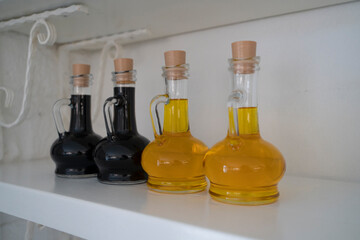 A small glass bottle of pomegranate sour sauce with extra virgin olive oil bottles isolated on white background under natural light.