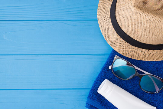 Summertime vacation time concept. Top above overhead view close-up photo of towel sunglasses sunhat and sunscreen isolated on blue wooden background with copyspace
