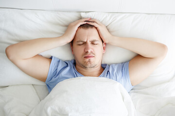 insomnia, depression or headache concept - top view of stressed man lying in bed