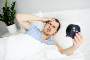 sleepy man waking up early after hearing alarm clock signal