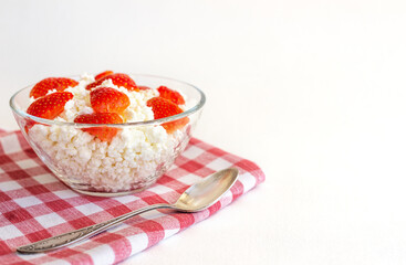 Fresh, homemade cottage cheese for Breakfast with strawberries, in a glass Cup, on a checked linen napkin, on a white background. The horizontal position, copy space
