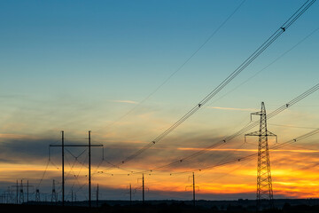 High-voltage power lines at sunset by the road. Horizontal