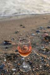 Glass of rose wine on the beach. Vertical image.