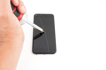 Eine männliche Hand mit einem Schraubenzieher hinterlässt einen dicken Kratzer auf der Handyoberfläche.