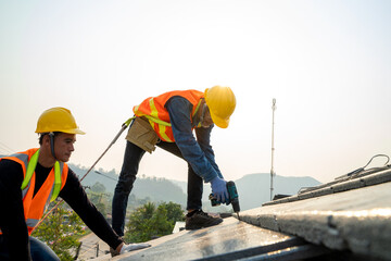 Construction worker wearing safety harness belt during working on roof structure of building on new roof.
