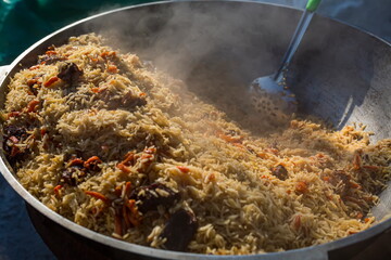Cook cooks pilaf in a cauldron. A man interferes with rice.
