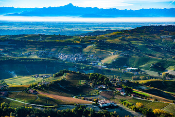 Autumnal aerial view of the Cuneo langhe, in the center the village of Barolo in the background the chain of the alps with the Monviso in the center - obrazy, fototapety, plakaty