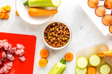 Dogfood set with vegetables, eggs and meat on table background top view