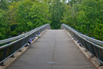 Fototapeta premium Pedestrian bridge over the river in the city of Ogre, in the background a green forest.