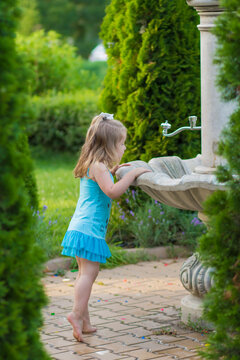 Thirsty little girl looking into a fountain in the park