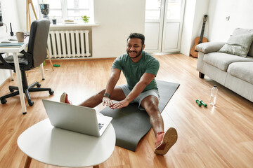 Cheerful stretching. Male fitness instructor showing exercises while streaming, broadcasting video...