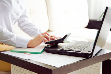 Close up Business woman using calculator and laptop for do math finance on wooden desk in office and business working background, tax, accounting, statistics and analytic research concept