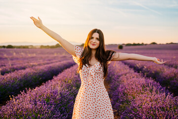 Happy woman in a dress and with open arms in lavender field.