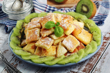 Austrian dessert Kaiserschmarrn served with sugar powder and kiwi fruit