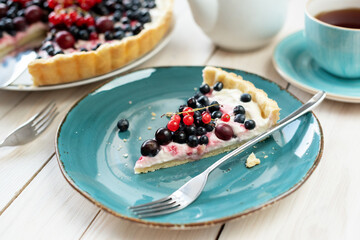 Blueberry open pie on blue plate close up with cup of black tea