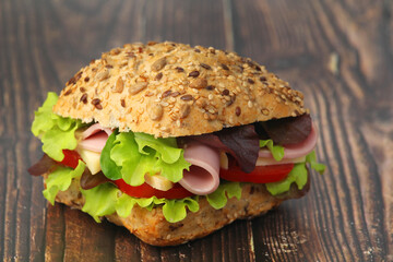 A sandwich with whole grain bread, ham and vegetables