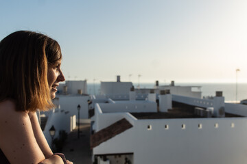 Fototapeta na wymiar Attractive young female witnessing the sunset from a viewpoint located in a small village in Cadiz, Spain