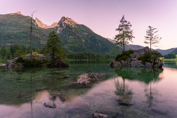 Beautiful scene of trees on a rock island and mountains at sunset time in summer, Lake Hintersee National park Berchtesgadener Land, Upper Bavaria, Germany, Europe