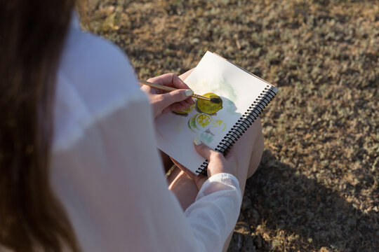 Girl artist paints a picture with watercolors in nature.