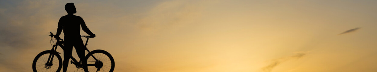 Conquering mountain peaks by cyclist in shorts and jersey on a modern carbon hardtail bike with an air suspension fork . Beautiful view from the mountain. Panoramic view for banner.