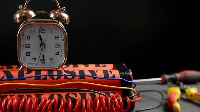 Dynamite bomb with clock timer on dark background, closeup