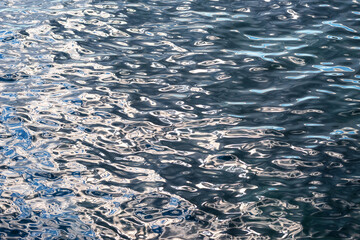 Abstract close-up texture of the sea surface with ripples and sun reflections