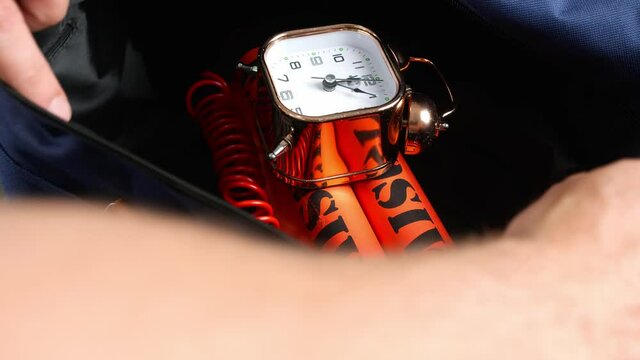 Man opening bag with dynamite bomb and clock timer, closeup