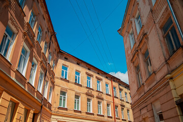 old city narrow street building walls foreshortening from below with vivid blue sky background in clear weather day