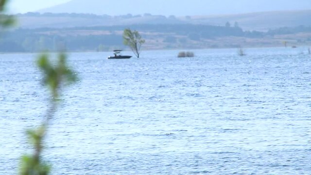 Enfoque-densenfoque de un barco navegando en un tranquilo lago azul en una tarde de verano.
