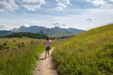 Girl walking along hiking trail at Alpe di Siusi – Seiser Alm.