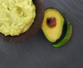 Guac in a traditional Mexican of stone mortar. (guacamole in molcajete) avocado and chili .grey background 