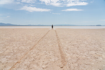 A man standing in the desert at the edge of standing water from recent rain.
