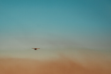 Fototapeta na wymiar Plane in the sky flying over dust clouds