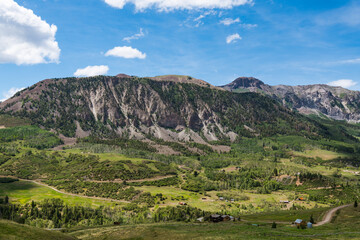Fototapeta na wymiar Rugged landscape of mountains, green fields, ranches, and buildings along Last Dollar Road near Telluride, Colorado