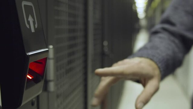 Close up. Man uses a fingerprint biometric access control scanner in high-security business environment.