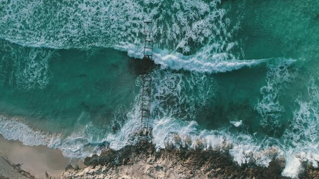 Pier with waves crashing into drone view