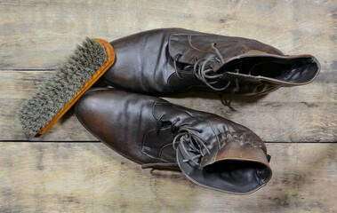 old leather shoes with shoe polish and  brushes against aged cracked wooden boards