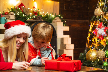 Fototapeta na wymiar Brother and sister on christmas. Cute little boy with sister writing letter to Santa Claus at home.