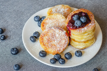 Syrniki or cottage cheese fritters with blueberry jam on a white plate	